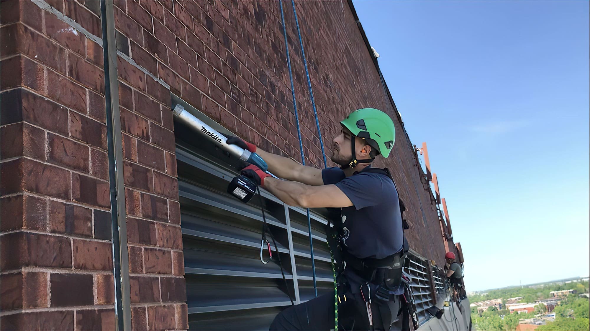 Travailleur en hauteur réparant façade en brique.