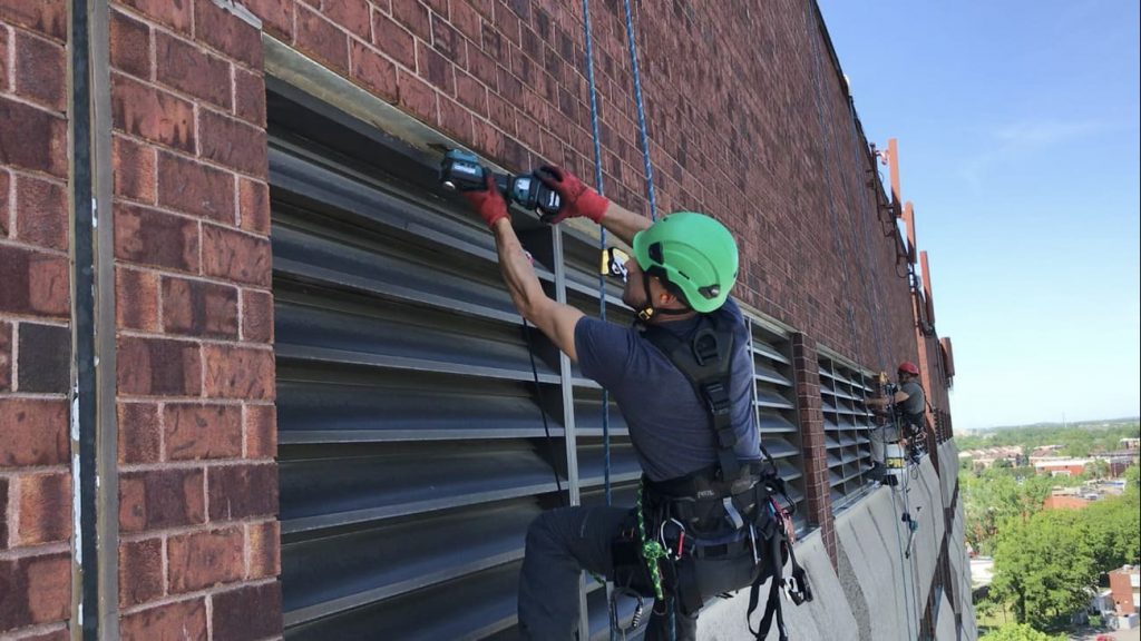Technicien en hauteur réparant une façade d’immeuble