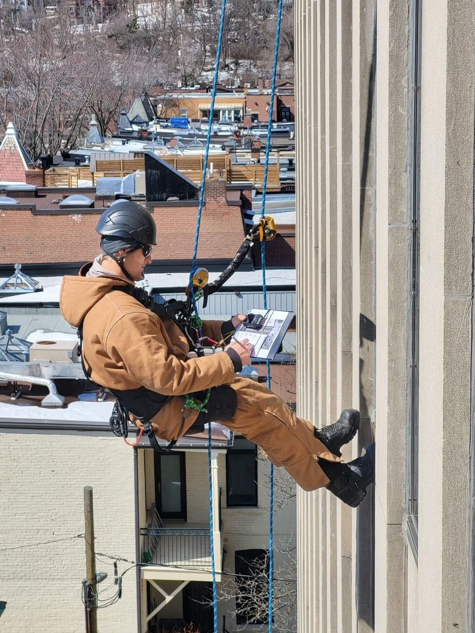 Travailleur suspendu inspectant la façade d’un bâtiment
