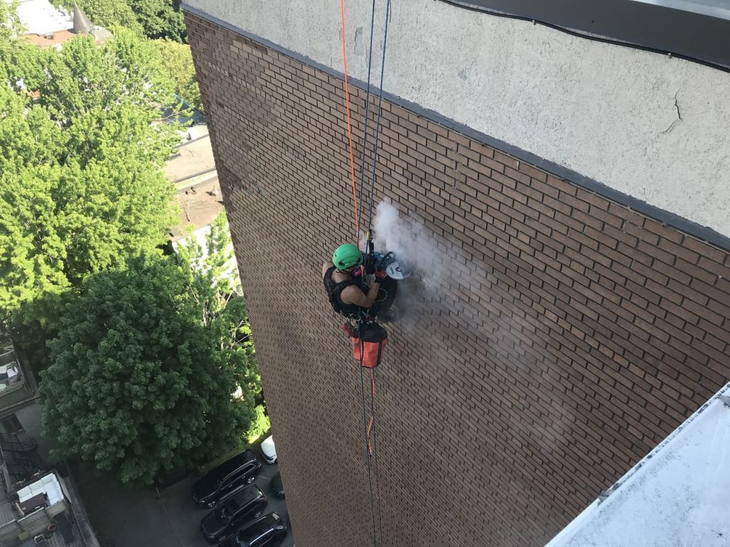 Suspended worker cleaning a brick wall